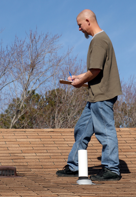 Roofer checking shingles during a roof inspection for homeowners in St. Louis