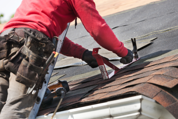 Roofer on a ladder making an emergency roof repair